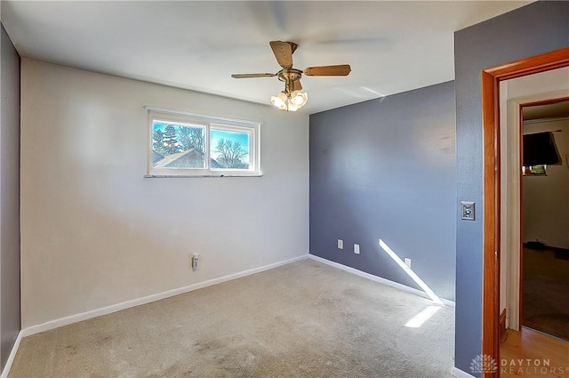 spare room featuring baseboards, a ceiling fan, and light colored carpet