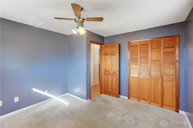 unfurnished bedroom with baseboards, ceiling fan, a closet, and light colored carpet