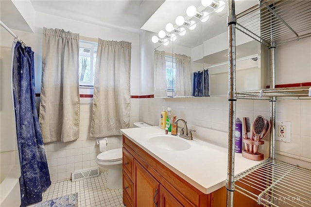 full bath with toilet, visible vents, vanity, tile walls, and shower / bath combo