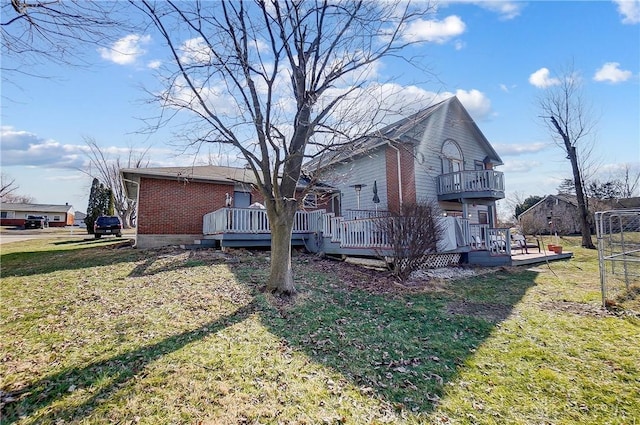 view of side of home featuring brick siding, a yard, and a wooden deck