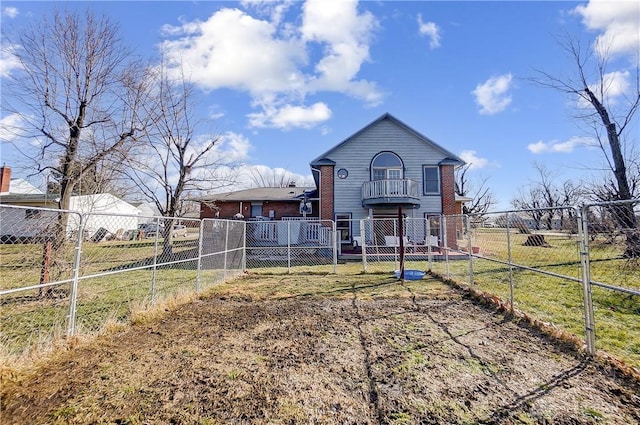 rear view of house with fence private yard, brick siding, a yard, and a balcony