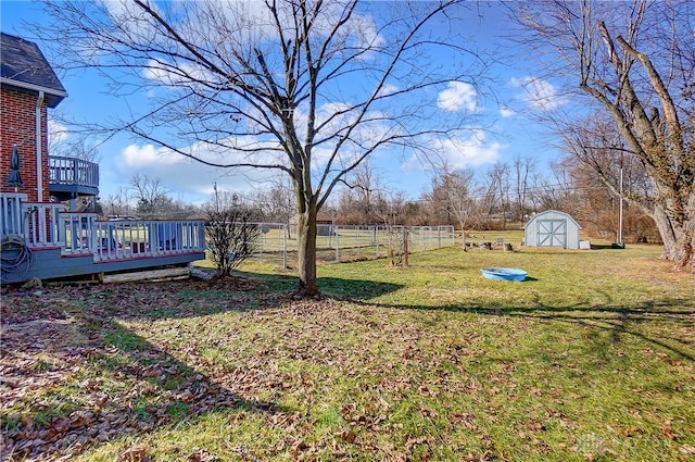 view of yard with a shed, an outdoor structure, a wooden deck, and fence