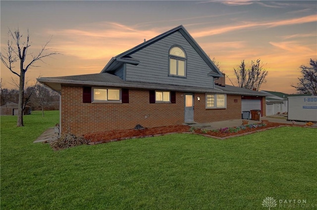 view of front facade featuring a garage, brick siding, a lawn, and a patio area