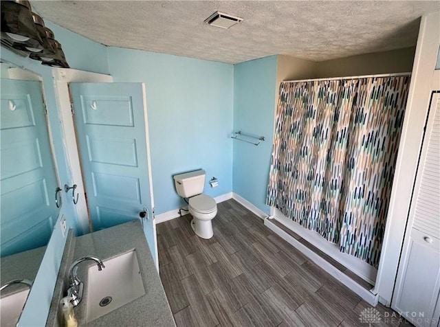 bathroom with curtained shower, hardwood / wood-style floors, sink, toilet, and a textured ceiling