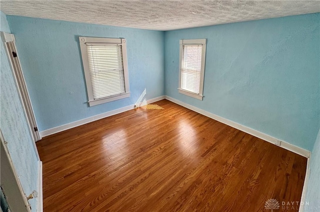 unfurnished room with wood-type flooring and a textured ceiling