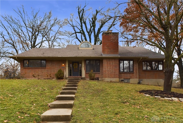 view of front of home with brick siding, a chimney, a front yard, and a shingled roof