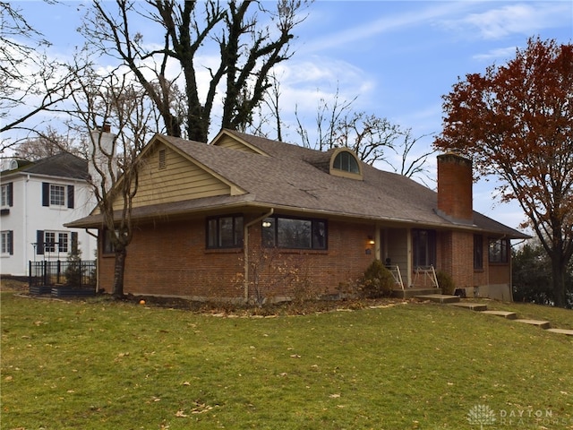 exterior space with a front lawn, a chimney, and brick siding