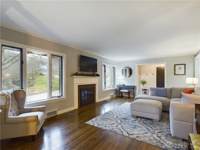 living room featuring crown molding, dark hardwood / wood-style flooring, and a brick fireplace