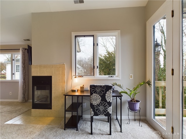 living area with a tiled fireplace and light carpet