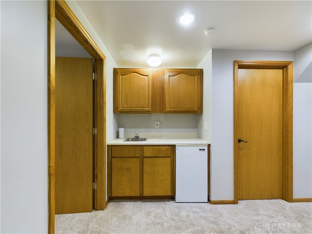 kitchen featuring dishwashing machine, sink, and light colored carpet