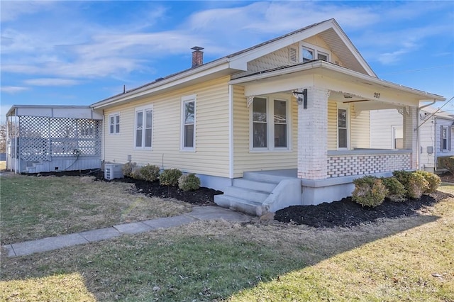 view of side of home with a yard, central air condition unit, and a porch