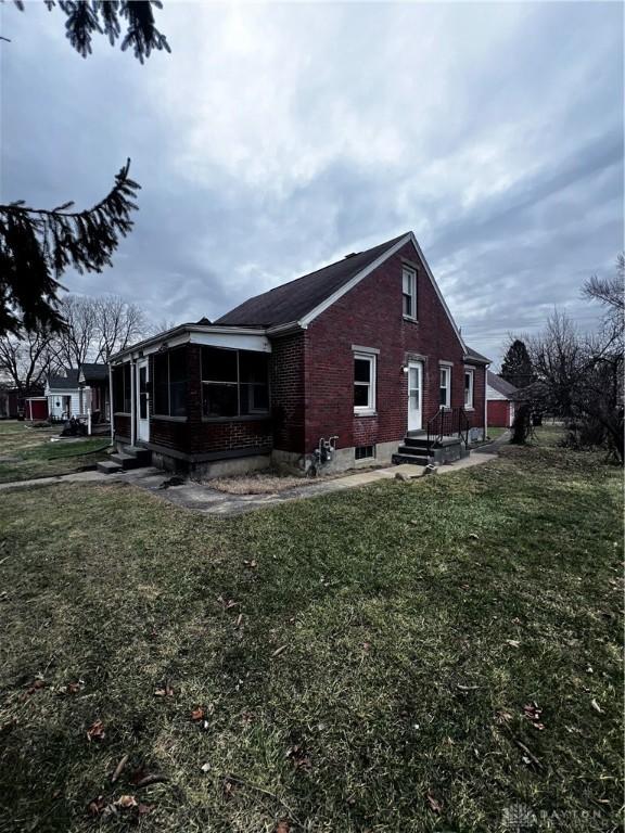 view of property exterior with a sunroom and a lawn