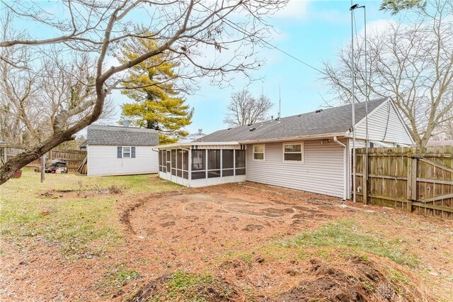 back of house with a storage shed, a sunroom, and a lawn