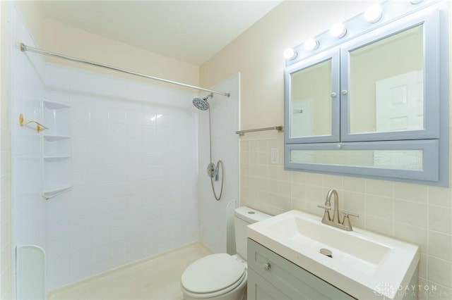 bathroom featuring tile walls, vanity, a tile shower, decorative backsplash, and toilet