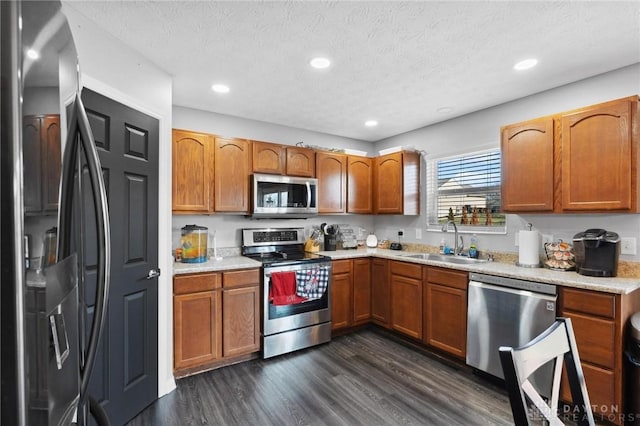 kitchen with appliances with stainless steel finishes, sink, a textured ceiling, and dark hardwood / wood-style flooring