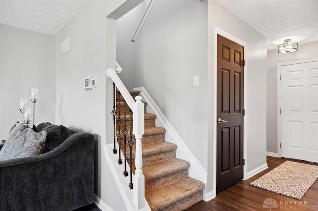 foyer entrance with dark hardwood / wood-style floors and a textured ceiling