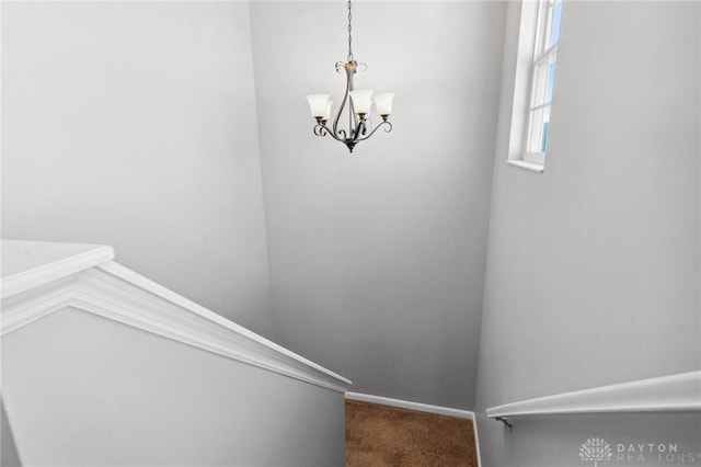 stairs with carpet flooring and a notable chandelier