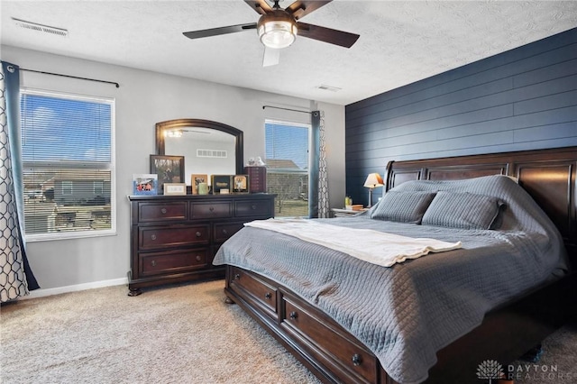 carpeted bedroom with ceiling fan and a textured ceiling