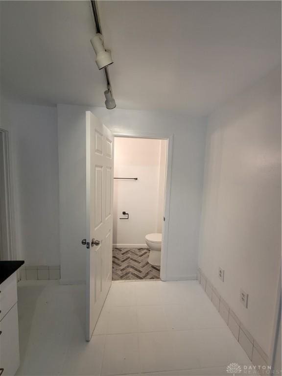 bathroom featuring track lighting, vanity, and toilet