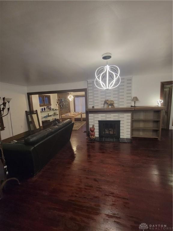 living room with an inviting chandelier, a fireplace, and dark hardwood / wood-style floors