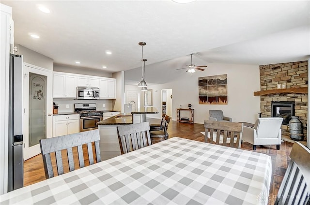 dining room with lofted ceiling, sink, dark wood-type flooring, and a fireplace