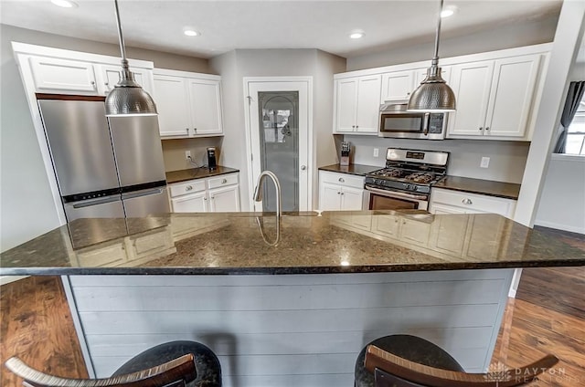 kitchen featuring a large island, decorative light fixtures, white cabinets, and appliances with stainless steel finishes