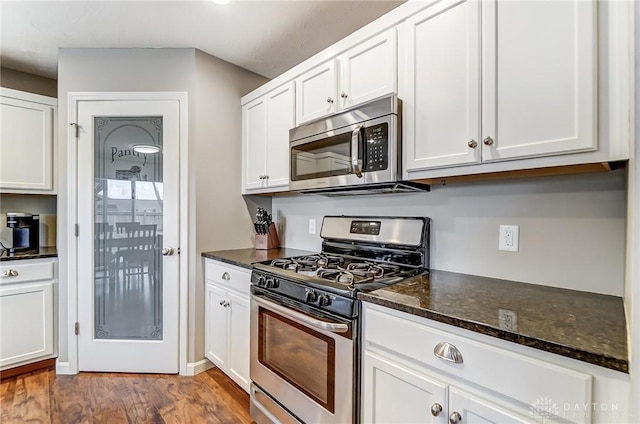 kitchen featuring dark stone countertops, stainless steel appliances, and white cabinets