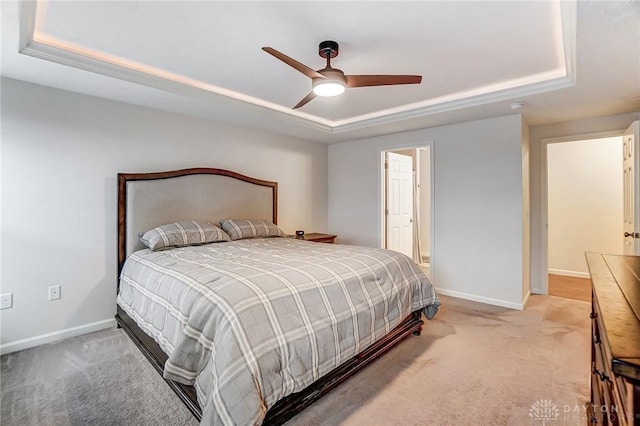 bedroom featuring ensuite bath, carpet flooring, ceiling fan, and a tray ceiling