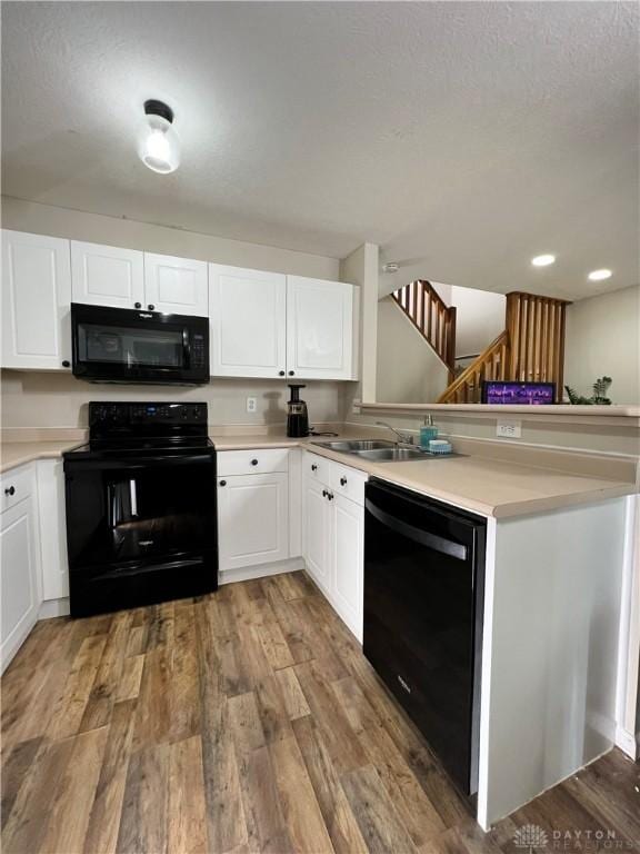 kitchen featuring white cabinetry, hardwood / wood-style flooring, sink, and black appliances