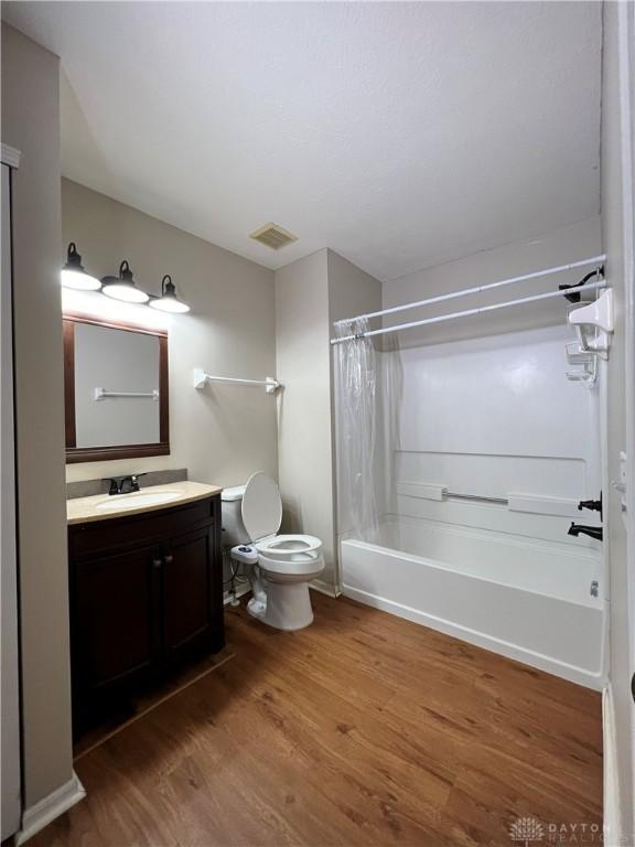 full bathroom with shower / bath combination with curtain, wood-type flooring, toilet, and vanity