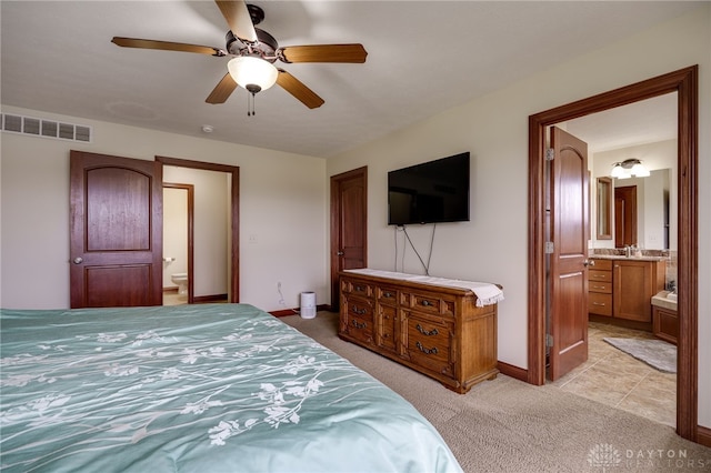 bedroom with ceiling fan, light carpet, and ensuite bath