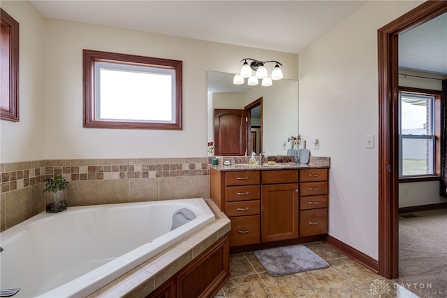 bathroom featuring tiled tub and vanity