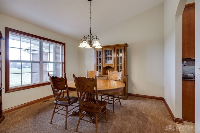 dining space featuring carpet floors, a chandelier, and vaulted ceiling