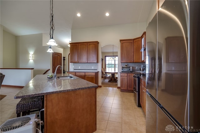 kitchen with pendant lighting, sink, a kitchen island with sink, stainless steel appliances, and tasteful backsplash