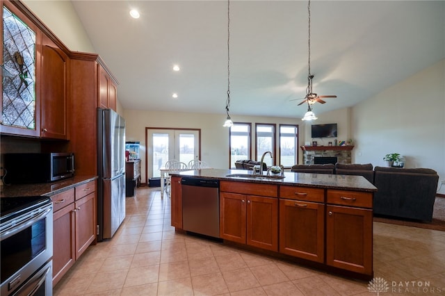 kitchen featuring pendant lighting, sink, appliances with stainless steel finishes, a stone fireplace, and vaulted ceiling