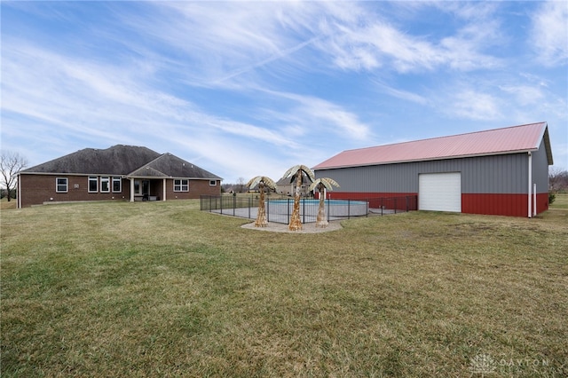 view of yard featuring a garage, a swimming pool, and an outdoor structure