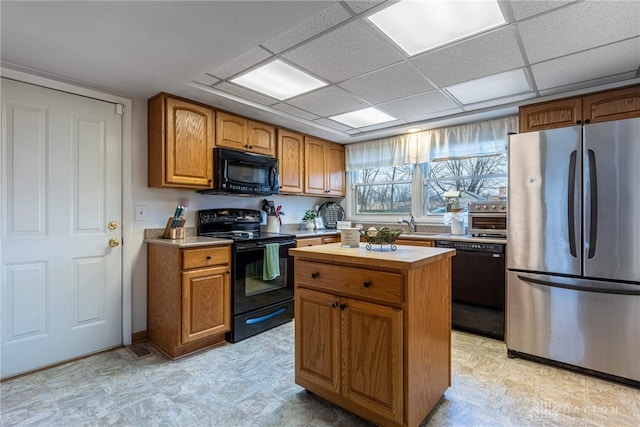 kitchen with a kitchen island, a drop ceiling, and black appliances