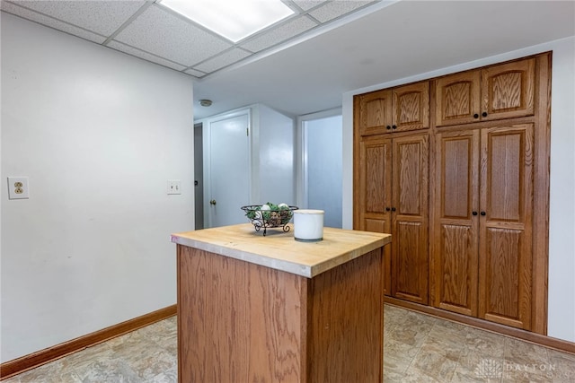 interior space with wood counters, a paneled ceiling, and a kitchen island