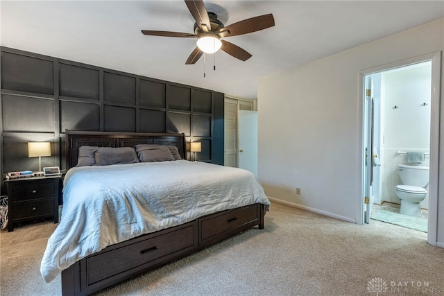 bedroom with ceiling fan, connected bathroom, light carpet, and tile walls