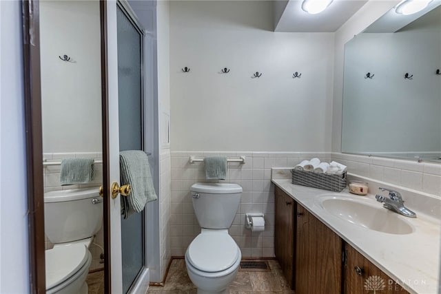 bathroom featuring vanity, an enclosed shower, tile walls, and toilet