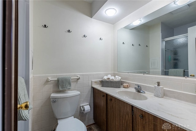 bathroom with vanity, a shower with shower door, tile walls, and toilet