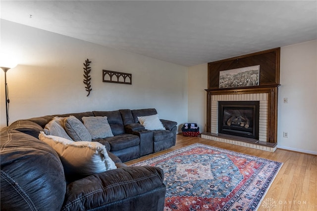 living room with a brick fireplace and light hardwood / wood-style floors