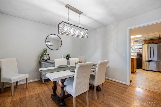 dining area featuring a paneled ceiling and light wood-type flooring