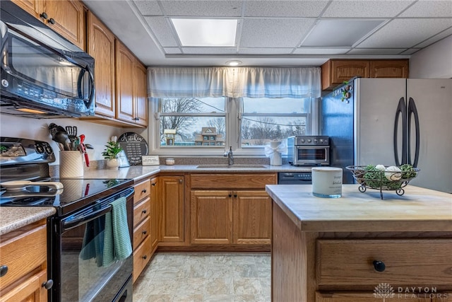 kitchen featuring a drop ceiling, sink, black appliances, and wooden counters