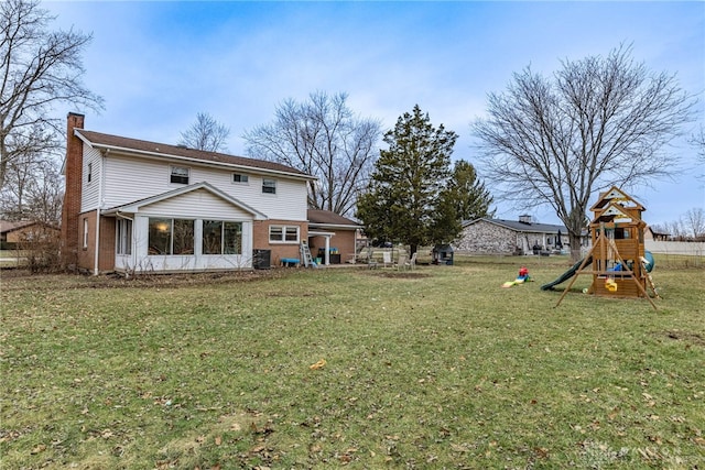 back of house with a yard and a playground