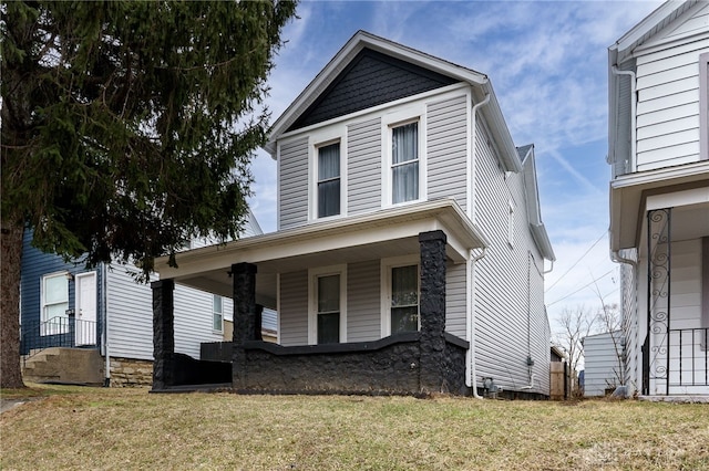 traditional-style home featuring covered porch and a front yard