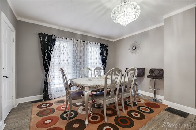 dining space with visible vents, baseboards, ornamental molding, wood finished floors, and a notable chandelier