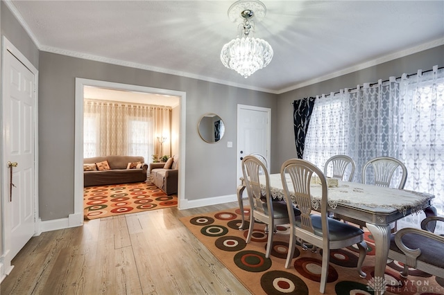 dining space with crown molding, a notable chandelier, wood finished floors, and baseboards