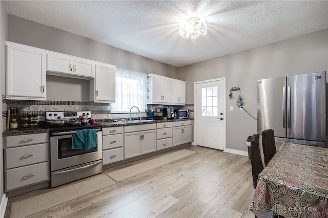 kitchen featuring plenty of natural light, dark countertops, appliances with stainless steel finishes, and light wood finished floors