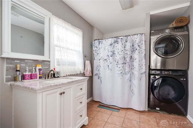 washroom featuring light tile patterned floors, laundry area, stacked washer and clothes dryer, and a sink